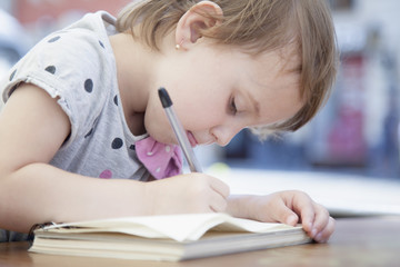 Little beautiful girl writing in her book (Education, knowledge, work, success concept)