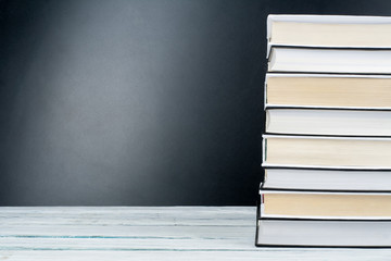Open books on wooden table, black board background. Back to school. Education business concept.