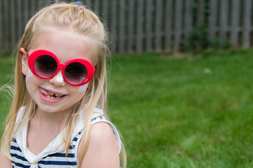 adorable school age girl with sunscreen and sunglasses on outside in summertime