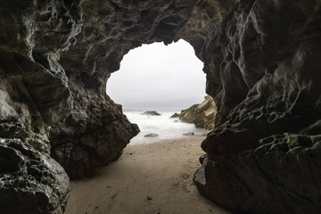 Sandy floor sea cave with motion blur water at Leo Carrillo State Beach in Malibu, California.   - obrazy, fototapety, plakaty