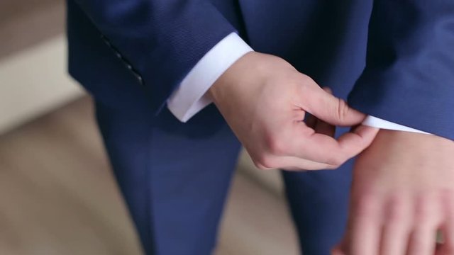 Successful man in the blue suit straightens his sleeves, close-up