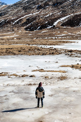 Kid stands on the frozen pond in winter at Zero Point at Lachung. North Sikkim, India.