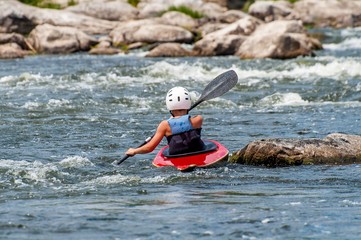 Obraz premium A teenager trains in the art of kayaking. Slalom boats on rough river rapids. The child is skillfully engaged in rafting.