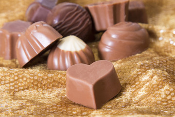 Assortment of chocolate bonbons on golden background
