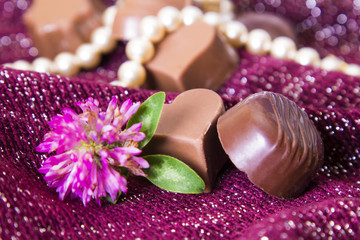 Obraz na płótnie Canvas Assortment of chocolates and pearl necklace