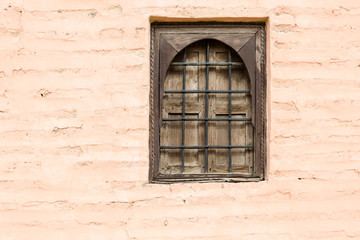 Old wooden rustic closed window with metal lattice