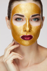 Cosmetic Mask. Beautiful Woman With Gold Mask Touching Face