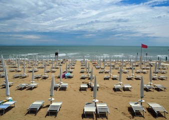 Early morning at the beach resort, with loungers,  closed umbrellas and red flag