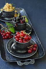 Composition of fresh ripe berries: red, black and white currants on a dark gray concrete background. Dark photo. Photographing in natural light. Space for your text