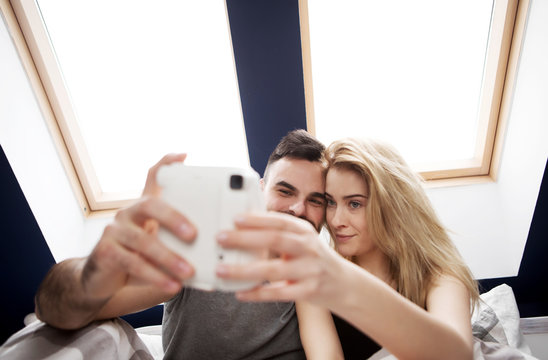 Couple Taking Selfie With Instant Camera At Home.