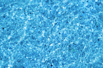 Obraz premium Crystal clear sea water ripples sparkling in the noon sun. Rippled water with bottom sand and shells seen underwater