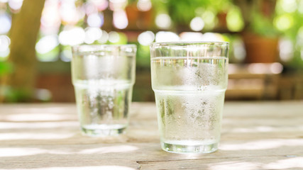 Two glass of water on a wooden table.