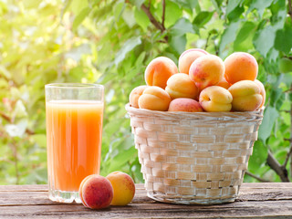 Apricots in a wicker basket and a glass of juice in the garden, sunlight