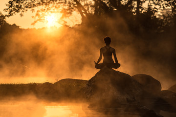 Silhouette of a beautiful Yoga woman in the morning at the hot spring park, soft and select focus