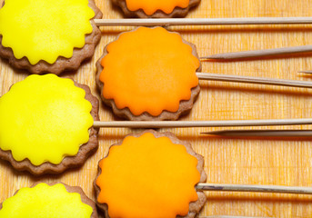 Gingerbread cookies with colored mastic on sticks on the old wooden cutting board