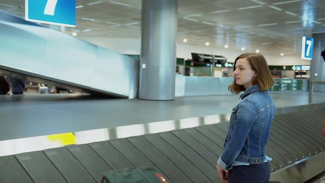 Young adult woman wait and pick up suitcase from luggage belt