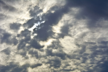 Gray sky with clouds with translucent rays of the sun.