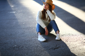 Stylish woman sitting on asphalt, outdoor, sunlight, street style