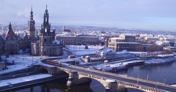 Aerial over the snow covered baroque city Dresden in Saxony, Germany - drone view over historical buildings and the bridge over the river "Elbe" in winter sunset 