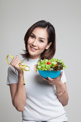 Healthy  Asian woman with measuring tape and salad.