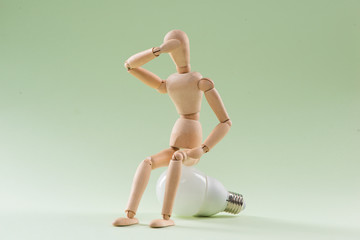 Having no idea. Wood figure mannequin sitting on an incandescent light bulb