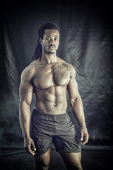 Fototapeta na wymiar African American bodybuilder man, naked muscular torso, wearing underwear, against black background