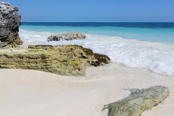 Horizontal landscape image from the Caribbean sea shore. Sunny summer day with no people. Some stones on the beach with wave hitting the rocks.