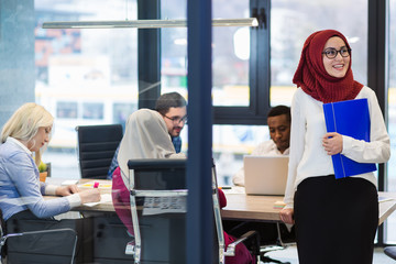Arabian Businesswoman in office with Businesspeople meeting in the background, Arabian woman wearing Hijab in office with her colleagues in background