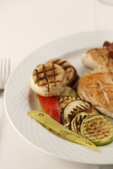 Chicken with bacon and grilled vegetables arranged on a plate, Traditional dish in elegant setting, Selective focus with soft light