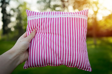 Pink striped pillow holding in hand closeup