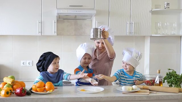 children cook in the kitchen with mom. three small children made a mess on the kitchen table