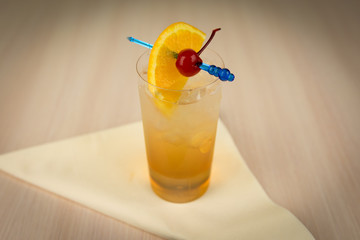 Cocktail from rye with cherry and orange on wooden table