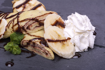 crepe with banana and chocolate on round slate stand