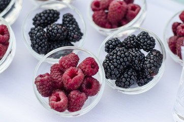 Ripe raspberries with blackberries in a glass cup