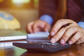 Businessman doing finances with using calculator and writing note in office.