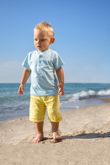 Beach,day,child posing in full growth on the sand of the sea.