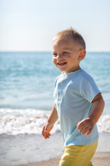 Fototapeta na wymiar Summer,bright day,the boy walks along the beach ,smiling and having fun.