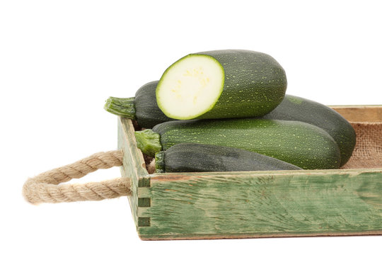 Green fresh zucchini in the wooden tray, isolated