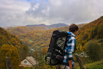 boy hiker walking on forest road with beautiful autumn mountain view wearing a big backpack