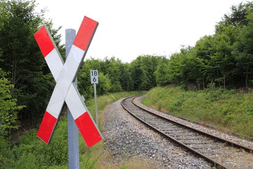 Andreaskreuz mit Blick auf die Bahnschienen, die in einer Rechtskurve verschwinden
