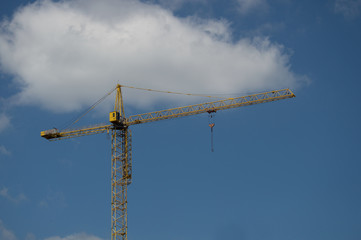 Yellow crane against the blue sky with a cloud
