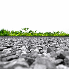 Backdrop of grey gravel stones with grass in outdoor space, low angle view.