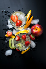 Fototapeta na wymiar Fresh summer drink, water with fruits and ice isolated on black