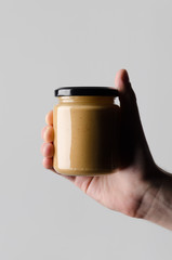 Peanut / Almond / Nut Butter Jar Mock-Up - Male hands holding a nut butter jar on a gray background
