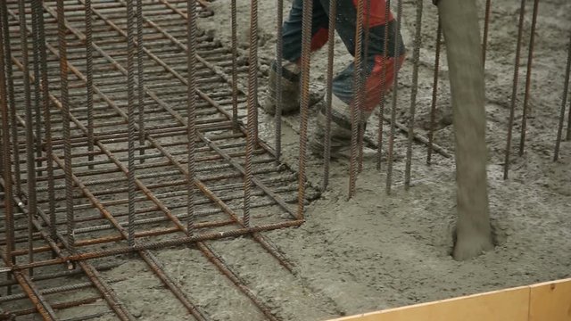 Pouring concrete mix from cement mixer on concreting formwork. Finished leveling the slab and pouring the concrete basement floor.