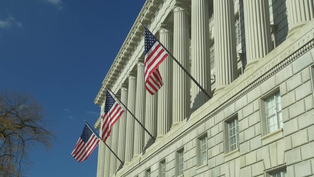 Low angle view of US National Flags on facade of US Department of Commerce in Washington DC