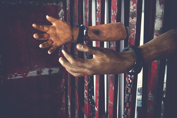 Human hand of ghost prisoner on steel lattice close up for Halloween background. Criminal hand show...