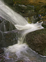 Close up of a section of a waterfall as it zigzags between wet rocks.