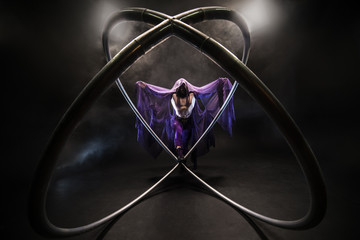 Fabulous character assassin in a purple cloak in the hood with two large cyr wheel hoops