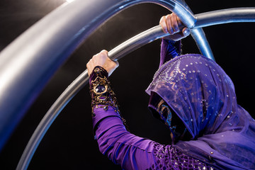 Fairy-tale character assassin in a purple cloak with a hood with two large metal hoops